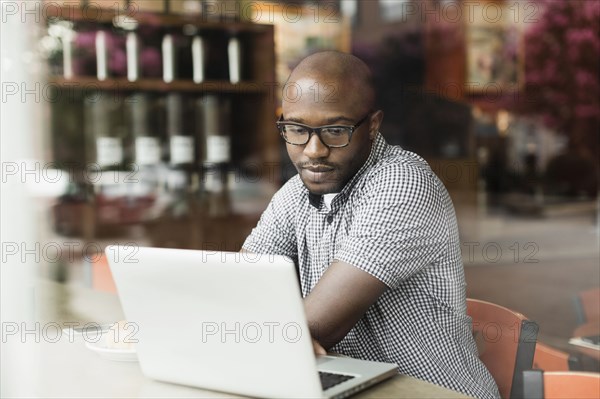 Black man using laptop in coffee shop