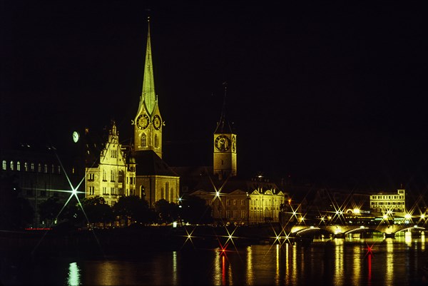 Old town buildings illuminated at night seen across river