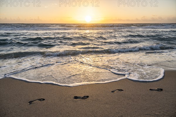 Footprints on beach at sunset