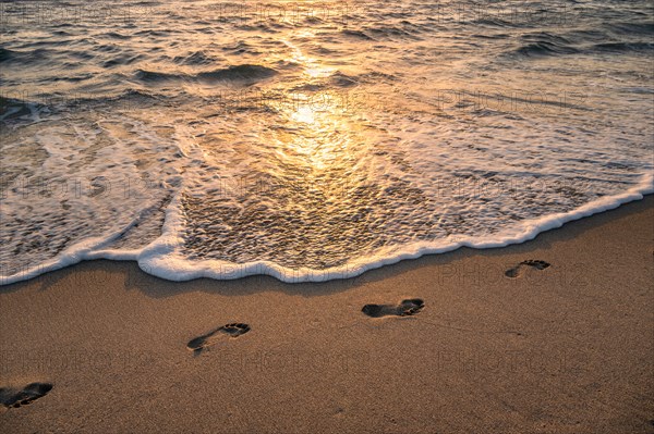 Footprints on beach at sunset