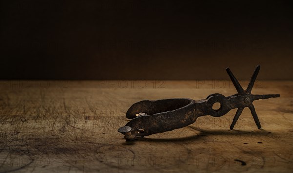 Old metal spur on wooden surface