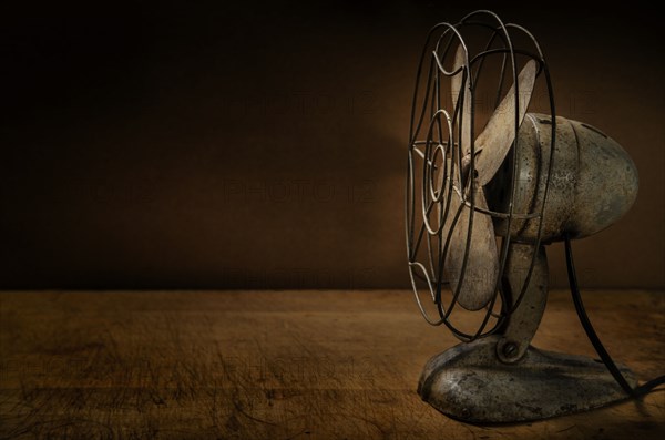 Old metal electric fan on wooden table