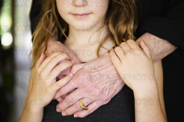 Close-up of grandmothers hand embracing granddaughter (8-9)