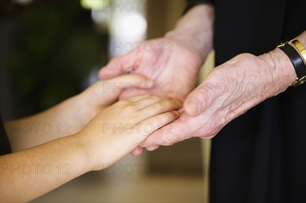 Close-up of grandmother and granddaughter (8-9) holding hands