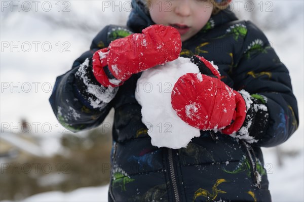 Boy (6-7) holding snowball