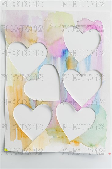 Studio shot of painted colorful paper with cut hearts