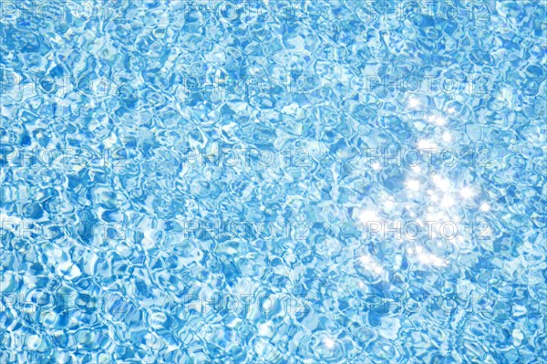 Sparkling reflections of sunlight on pool water surface