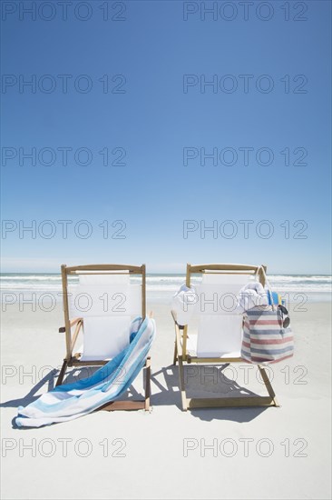 Empty beach chairs with bag and towel on beach