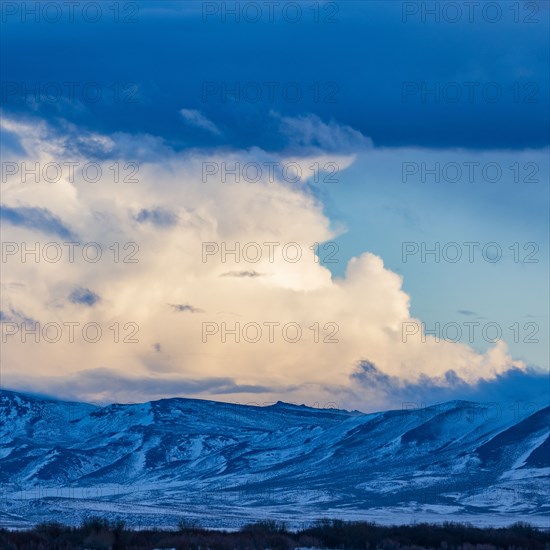 Snow dusted mountains and clouds over prairie