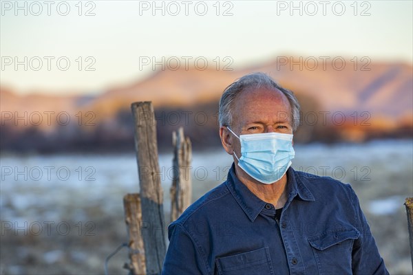 Outdoor portrait of senior man wearing COVID protective mask