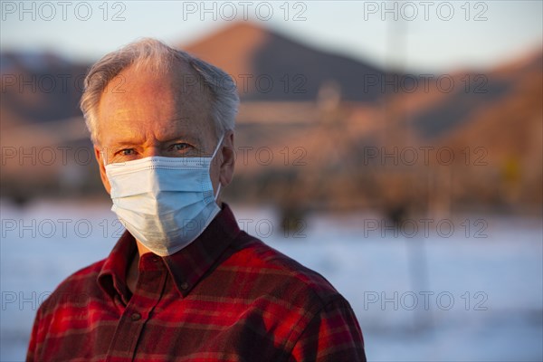 Outdoor portrait of senior man wearing COVID protective mask