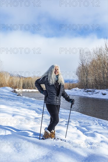 Senior woman with long white hair in snowshoeing in winter landscape