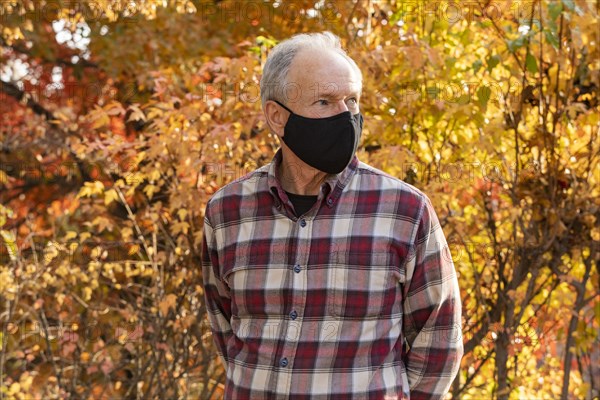 Senior man wearing protective mask in autumn park