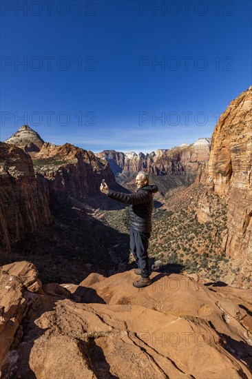 Senior man using phone at overlook of Zion Canyon in Zion National Park