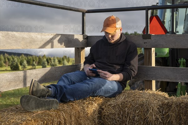 Young man resting on hay on tractor trailer