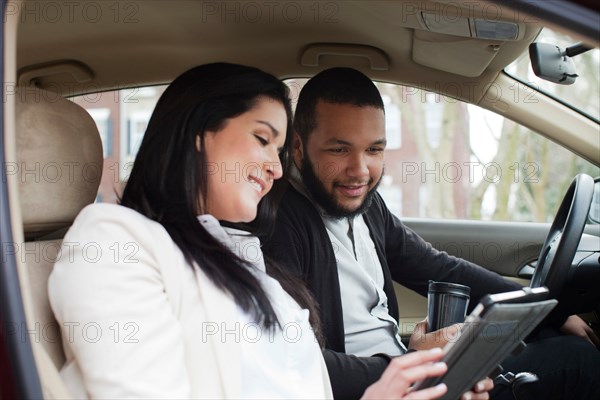 Young couple in car with digital tablet