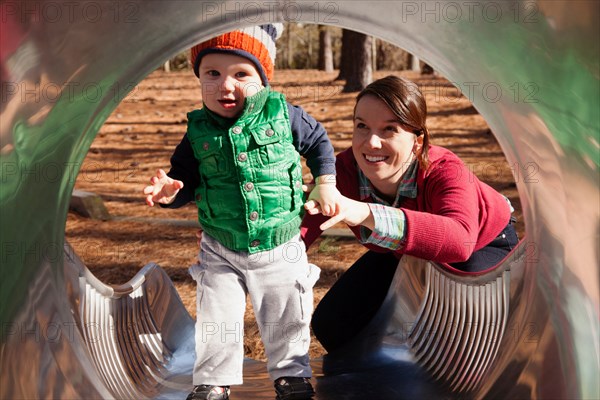 Mother helping son play on slide