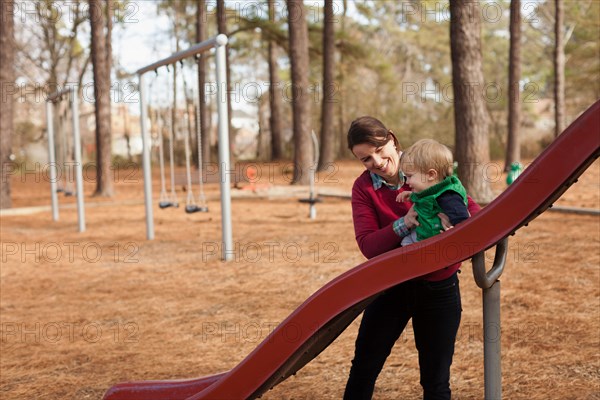 Mother helping son play on slide