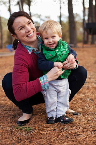 Laughing mother tickling son in park