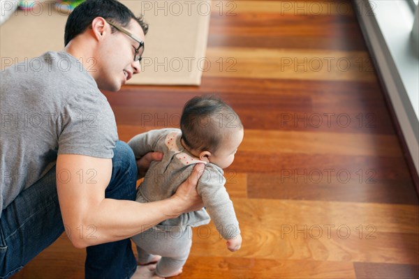Father supporting baby girl to walk
