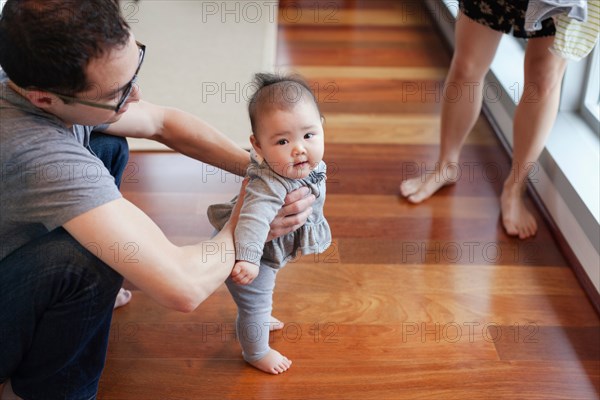 Father helping baby girl to stand