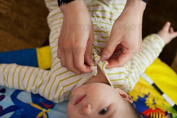 Close up of mother dressing baby daughter