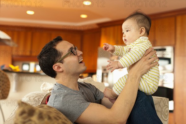 Close up of father sitting on sofa with baby daughter