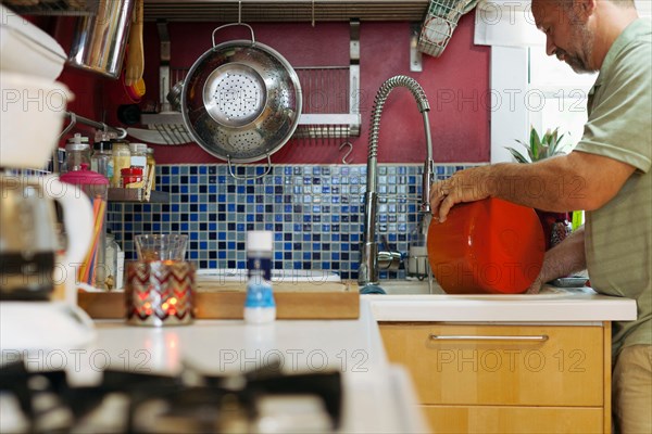 Man washing red pot