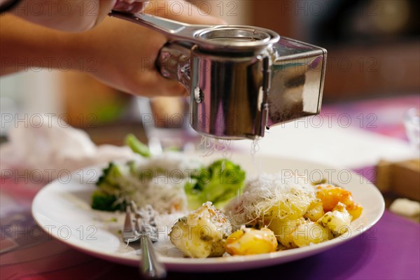 Grating cheese onto gnocchi