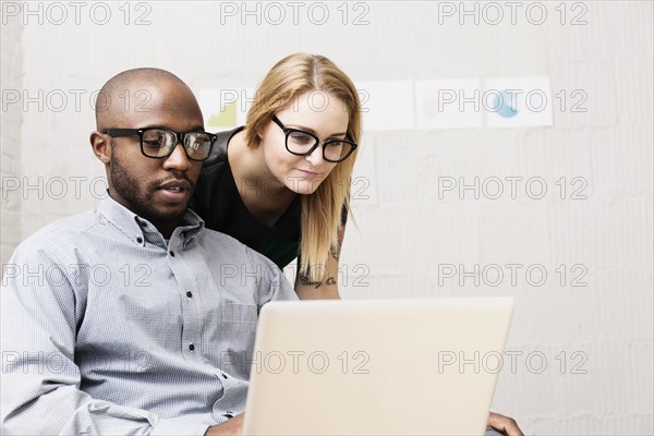 Young business partners looking at computer in design office