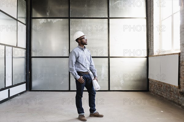 Portrait of young male interior designer in empty room