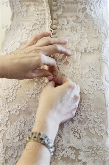 Bride being helped to get into wedding dress