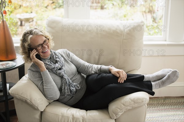 Relaxed senior woman sitting on chair talking on mobile