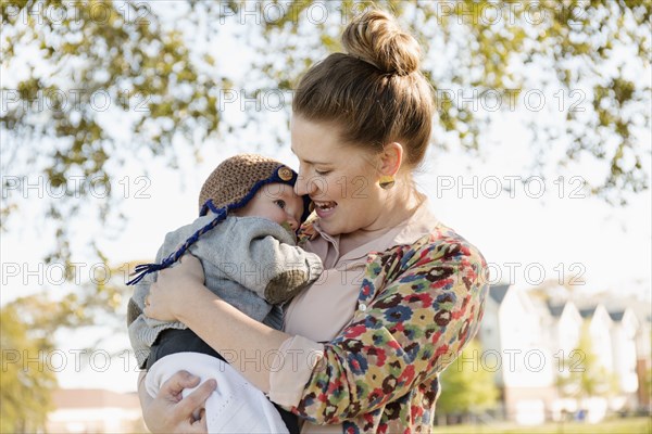 Mid adult mother carrying baby son in park