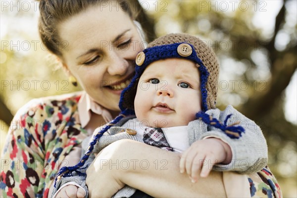 Close up of mid adult mother carrying baby son in park