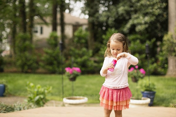 Female toddler preparing to blow bubbles in garden