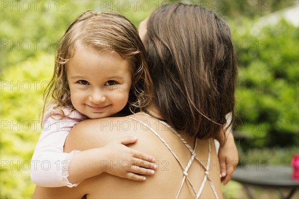 Portrait of female toddler carried by mother in garden