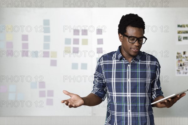 Young man holding digital tablet with arms out