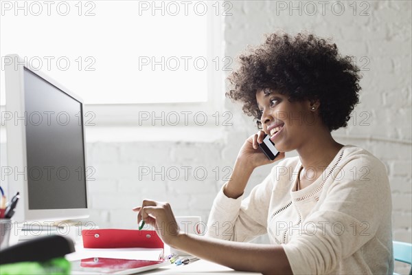 Young woman on smartphone at desk