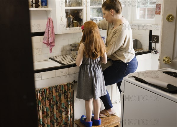 Girl and mother baking together in kitchen