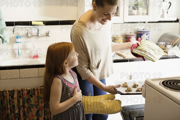 Girl and mid adult mother baking biscuits