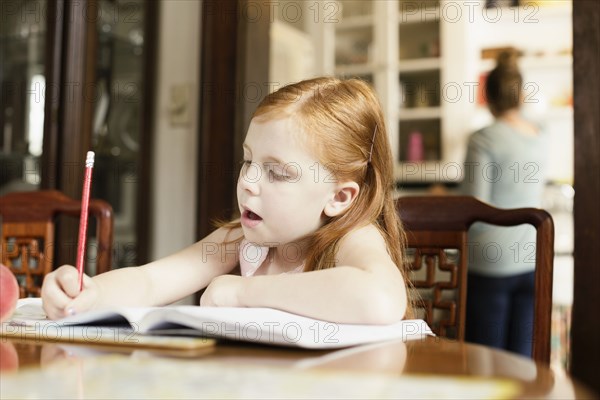 Girl doing homework at dining room table