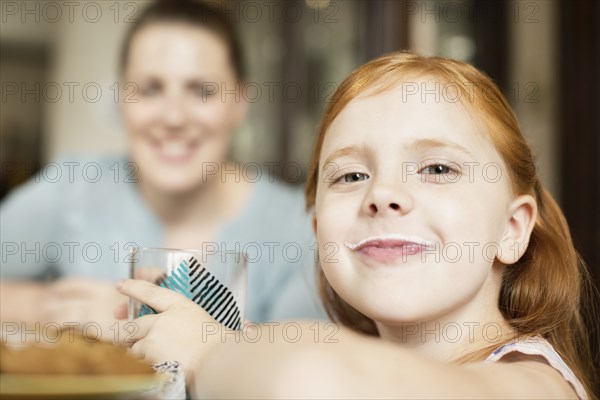 Girl with a milk moustache at dining room table