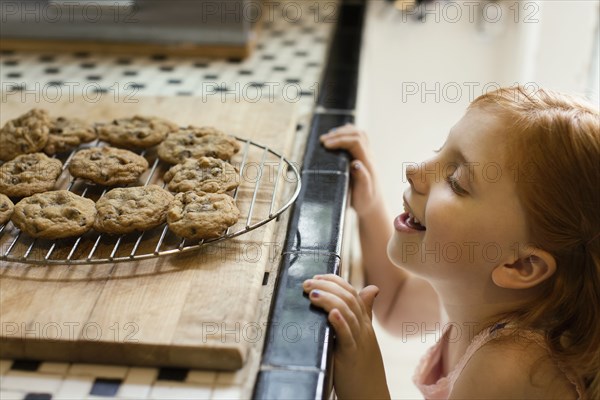 Girl peeking over kitchen counter at biscuits