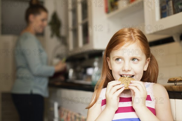 Girl eating biscuit in kitchen