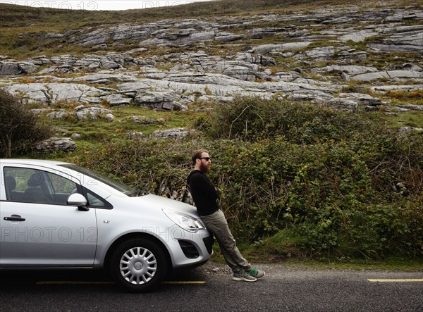 Mid adult man leaning against car bonnet