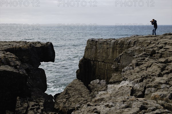 Mid adult man taking photo on cliff