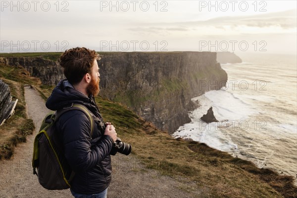 Mid adult man on The Cliffs of Moher with camera