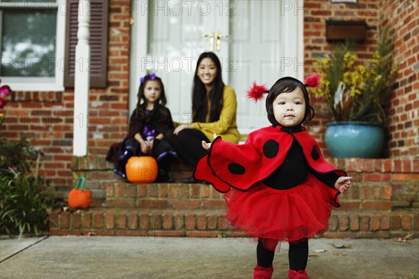 Girl dressed as ladybird outside house