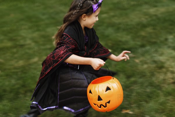 Girl in fancy dress costume with trick or treat bucket